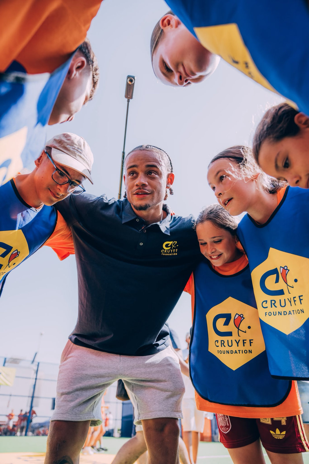 Xavi Simons with kids in Cruyff Foundation bibs at a Cruyff Court